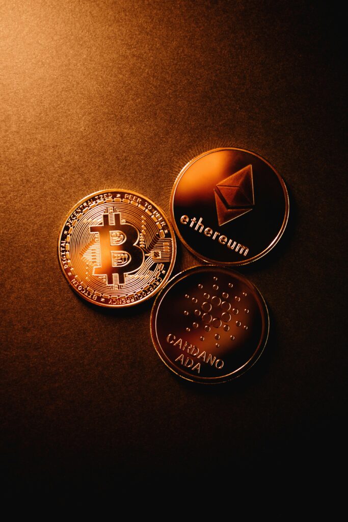 Close-up of Bitcoin, Ethereum, and Cardano coins arranged on a metallic copper background.